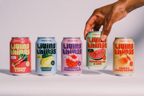 Row of Living Things prebiotic soda cans in different flavors with a hand picking one can
