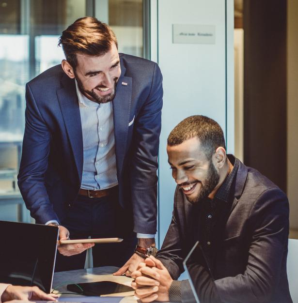 Two business professionals collaborating in an office, reviewing work on a tablet and laptop