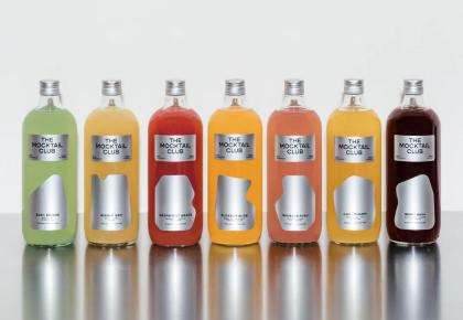 Lineup of The Mocktail Club bottled cocktails in various colors on a reflective surface